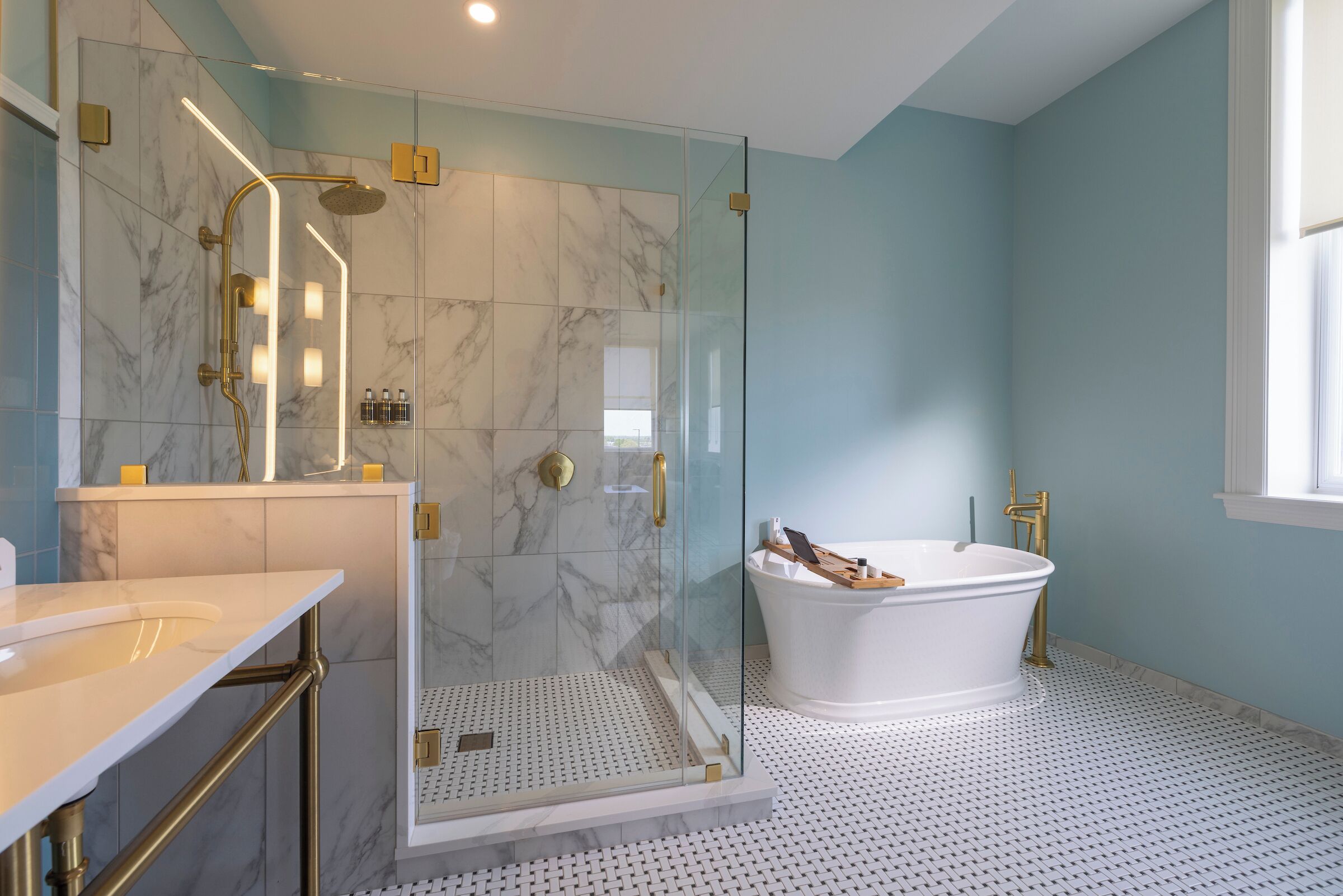 A bathroom with a glass-enclosed shower, a freestanding bathtub, and a marble-tiled floor.