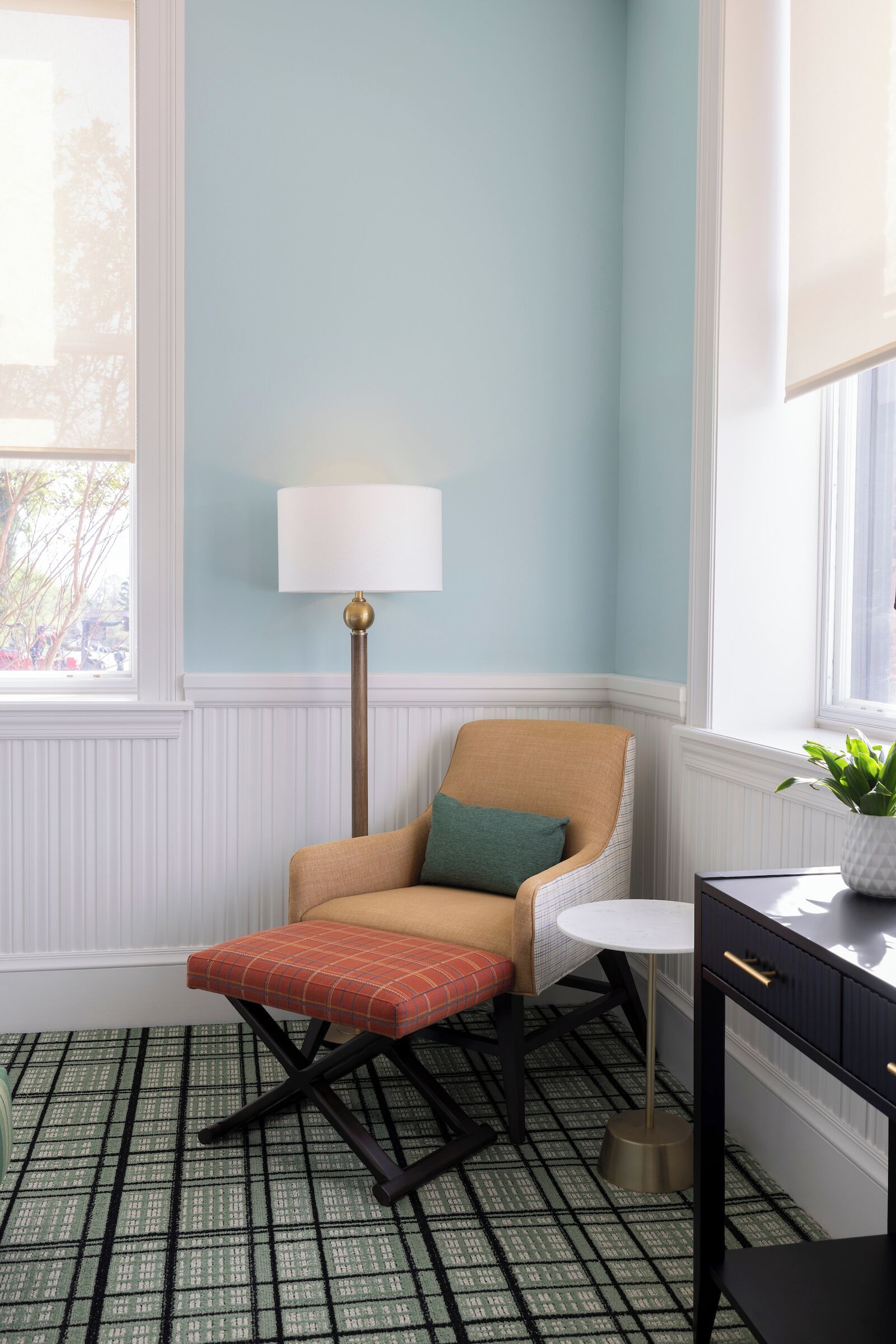 A room with a chair, a lamp, a small table, and a potted plant.