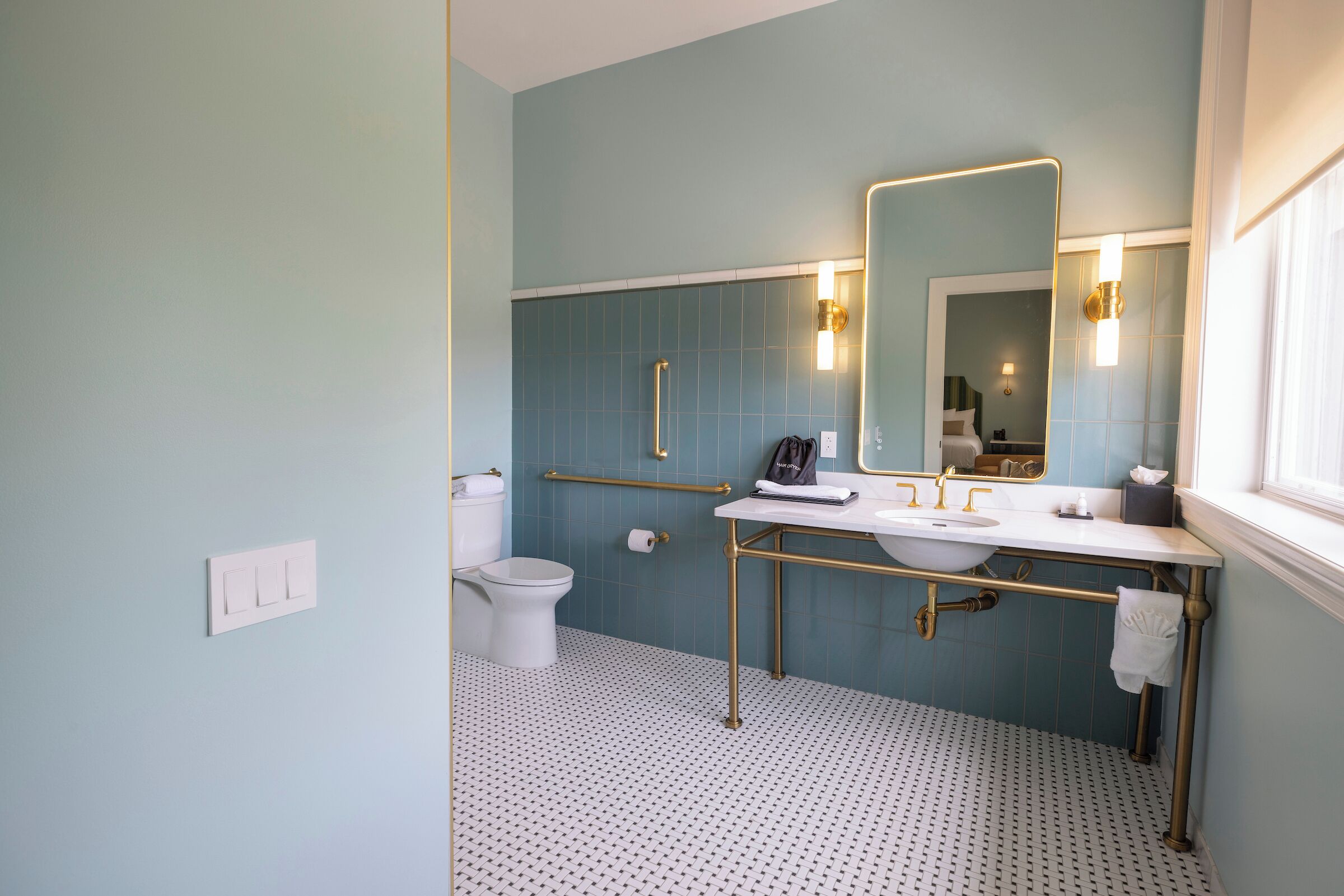 A bathroom with a white toilet, a sink with a gold faucet, and a mirror with a gold frame.