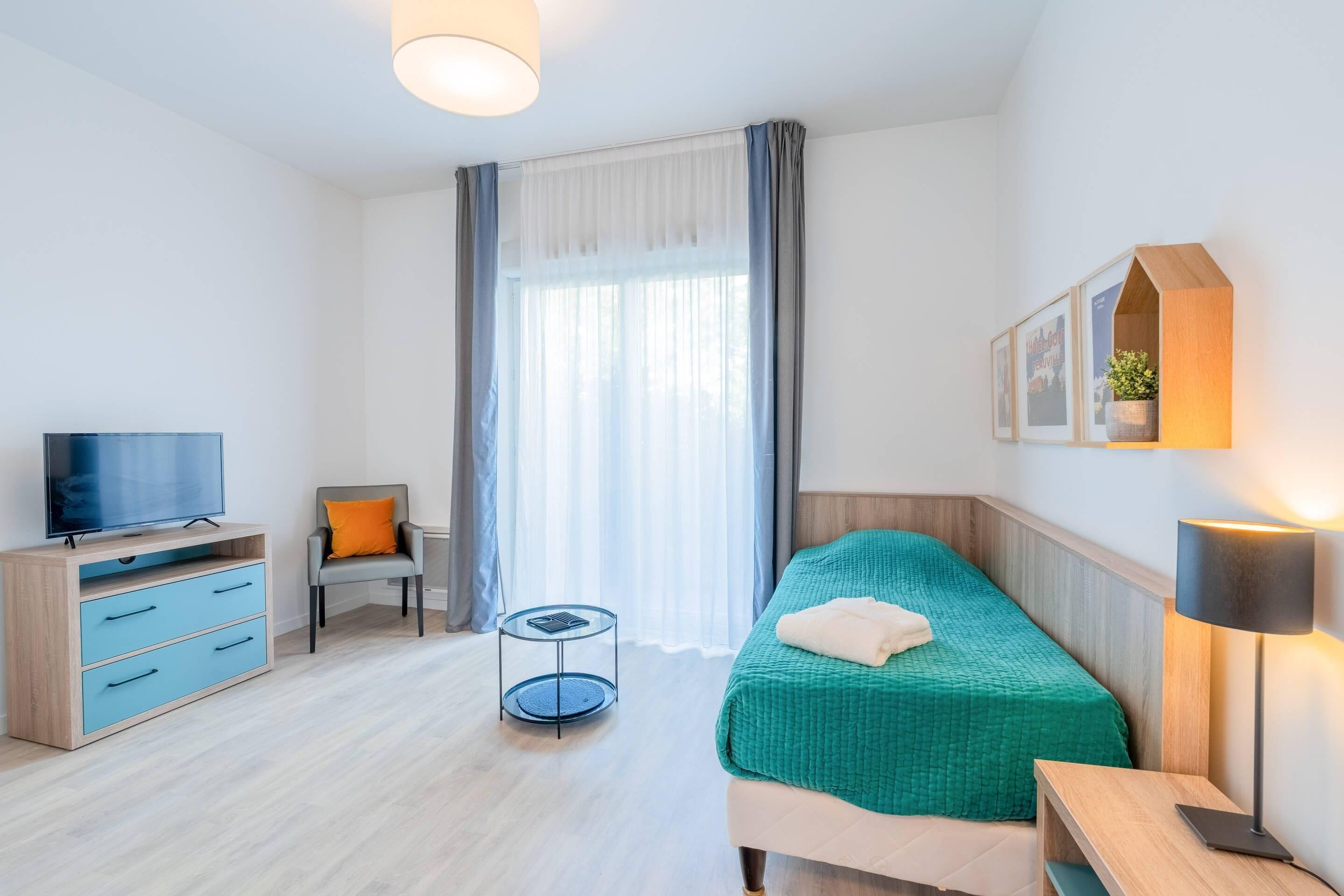 Habitació d'hotel moderna amb un llit, una televisió, un escriptori i una cadira.