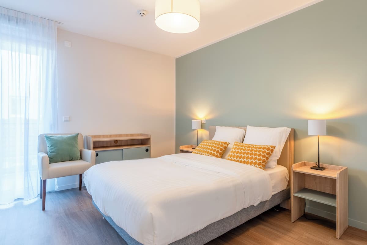 A bedroom with a bed, bedside tables, a chair, and a desk.