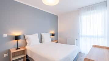 Ein modernes Schlafzimmer mit einem großen Bett, zwei Nachttischen mit Lampen, einer Holzbank und einer Heizung.