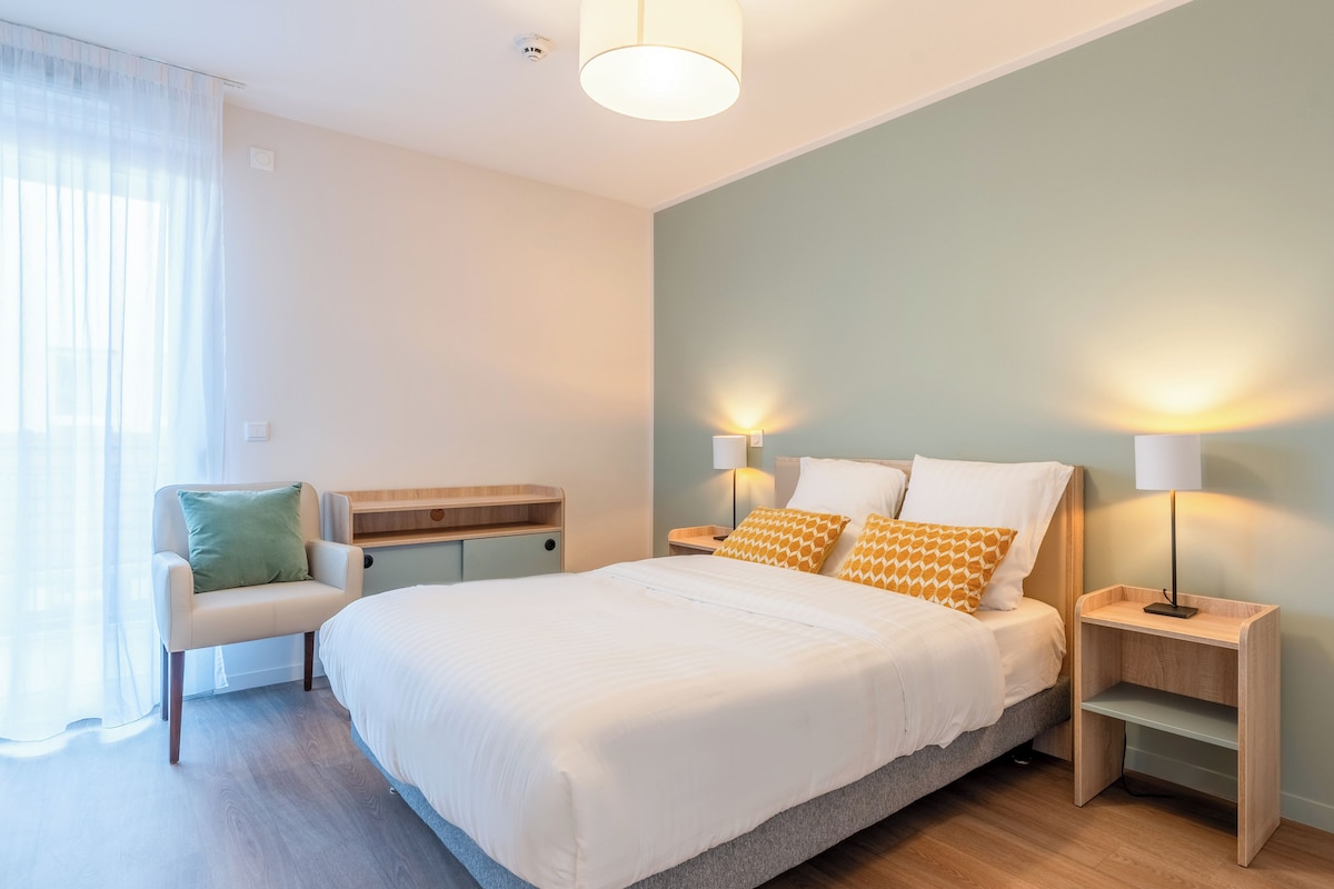 A bedroom with a bed, bedside tables, a chair, and a desk.