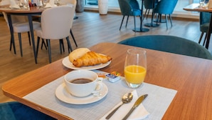 Desayuno con un croissant, café y jugo de naranja sobre una mesa de madera.