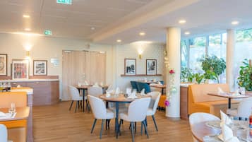 Un restaurant moderne avec des tables rondes, des chaises blanches et un plancher en bois.