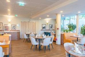 Un restaurante moderno con mesas redondas, sillas blancas y suelo de madera.