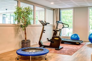 A home gym with a treadmill, exercise balls, a trampoline, and a potted plant. - Quality Aparthotel Choisy Orly Airport (Choisy-le-Roi)
