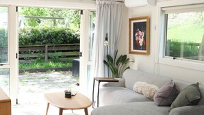 A living room with a grey sofa, a round wooden coffee table, and a white fluffy ottoman. - Queenstown House in Arthurs Point (Queenstown)