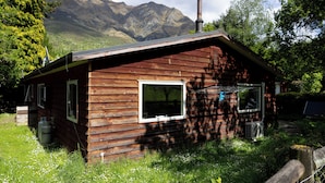 A wooden cabin with two windows, a chimney, and a gas cylinder. - Queenstown House in Arthurs Point (Queenstown)