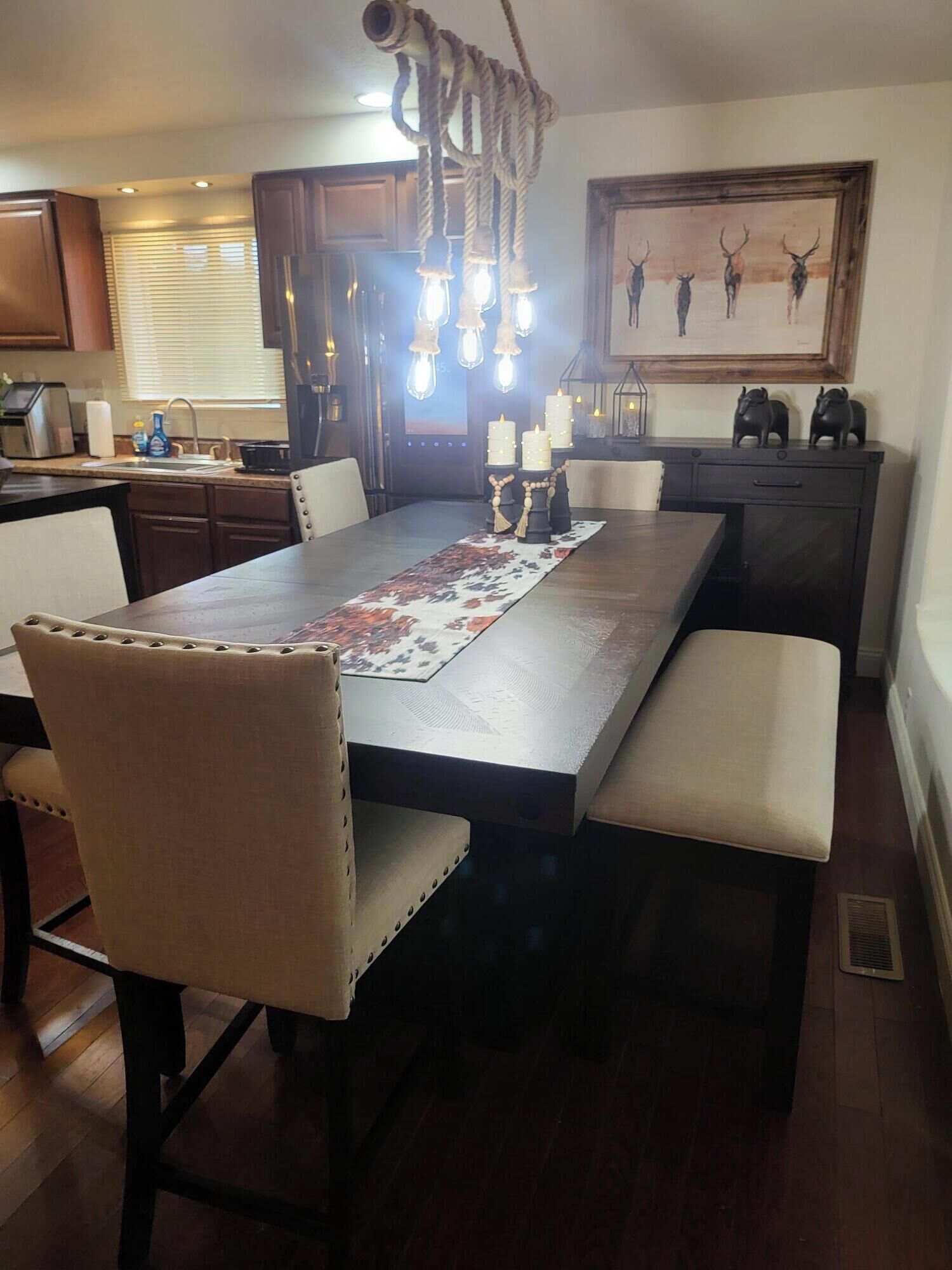 A dining area with a long table, cushioned chairs, a decorative runner, and a unique rope chandelier.