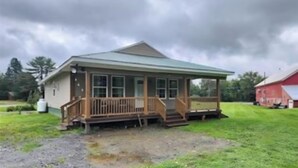 A single-story house with a porch, a green roof, and a grassy yard. - Ride from your door Atv Trails & Swim,Fish in Tug Hill Plenty of Trailer Parking (Redfield)