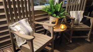 A wooden rocking chair with a cushion, a small table with a potted plant and a lantern, and a window with blinds. - Ride from your door Atv Trails & Swim,Fish in Tug Hill Plenty of Trailer Parking (Redfield)