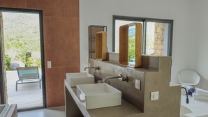 Casa de banho moderna com uma janela ampla, um banco do lado de fora e vista para vegetação.