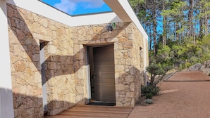 Um edifício moderno com fachada de pedra, deck de madeira e uma porta.