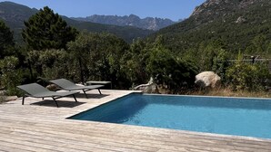 Piscina com espreguiçadeiras e vista para montanhas.