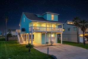 Ein zweistöckiges Haus mit Balkon, überdachter Veranda und Auffahrt.