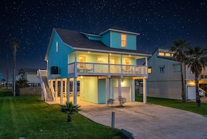 A two-story house with a balcony, a covered porch, and a garage. - 3-Level Beach House with Game Room & Ocean Views (Galveston)