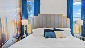 Ein Hotelzimmer mit einem großen Bett, blauen Vorhängen und einem Stadtbild-Wandgemälde.