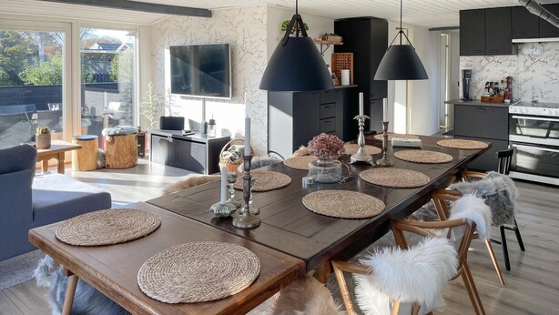 A modern dining area with a long wooden table, woven placemats, and a central decorative piece.