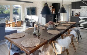 A modern dining area with a long wooden table, woven placemats, and a central decorative piece. - Ocean front home in Otterup with WiFi (Otterup)