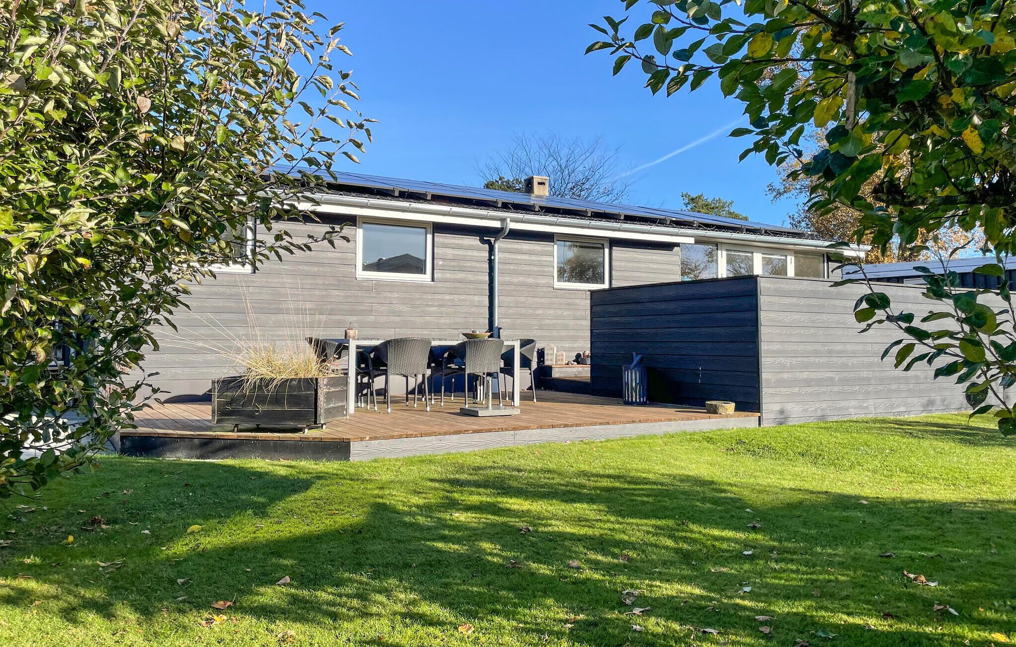 Une maison moderne dotée d’un patio, d’un barbecue intégré et d’une grande fenêtre donnant sur la cour.