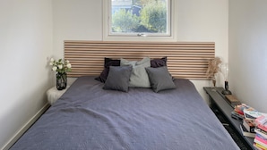 A bedroom with a bed, bedside table, and a window.