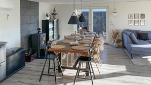 A modern kitchen with a central island, a built-in stove, and a dining area with a long table set for six.