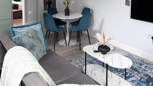 A modern living room with a grey sofa, teal chairs, a white coffee table, and a chandelier. - Modern Flat • Castle Views & Free Parking (Dover)