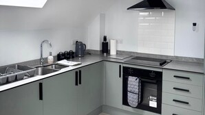 A modern kitchen with a skylight, a built-in oven, and grey cabinetry. - Modern Flat • Castle Views & Free Parking (Dover)