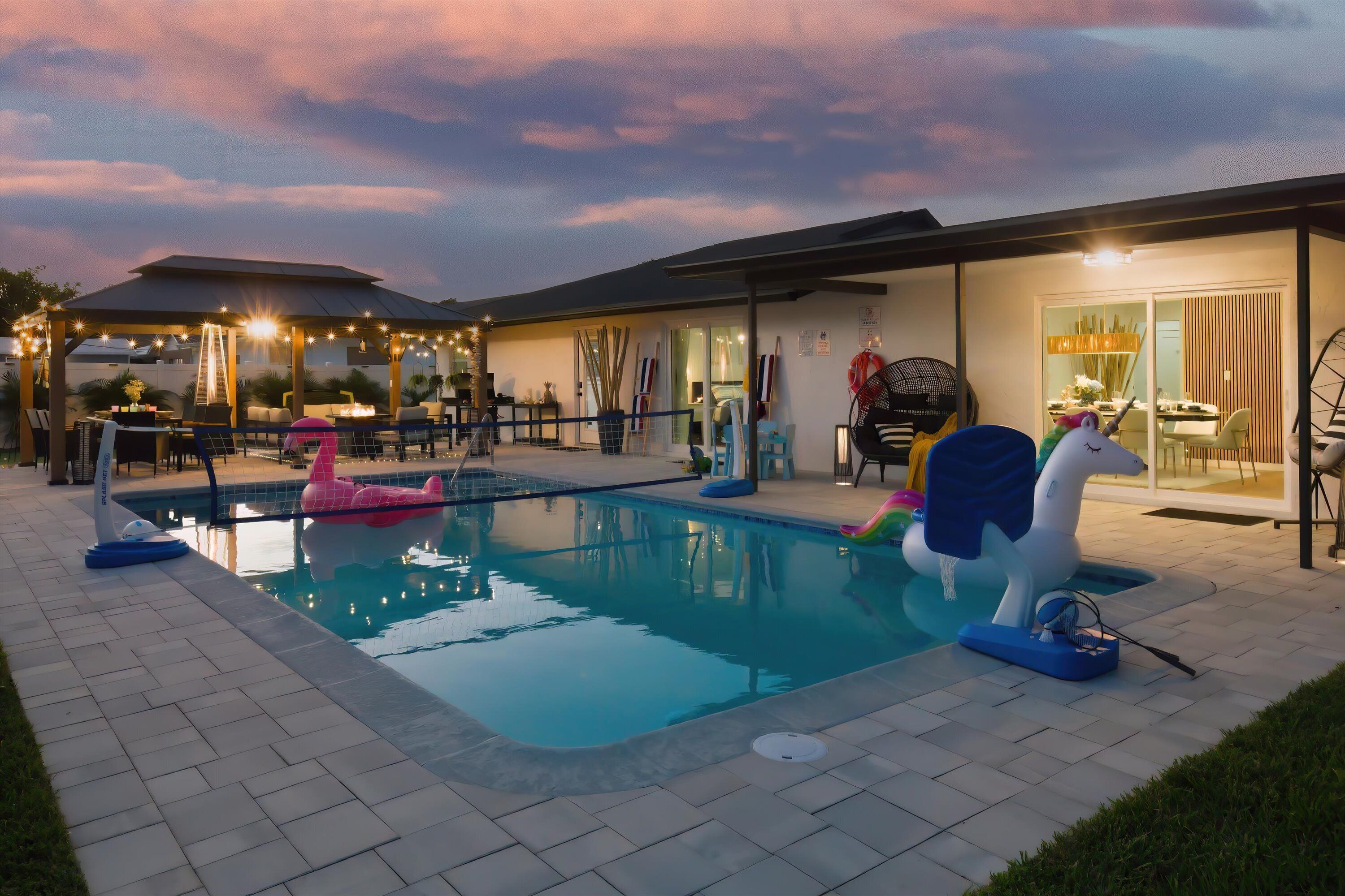 A swimming pool with inflatable toys, a covered patio area, and a dining space with outdoor seating.
