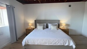 A bedroom with a large bed, two bedside tables with lamps, a wooden ceiling, and a window with curtains. - Beautiful and quiet house Los Quemados, Fuencaliente de La Palma. (fuencaliente de la palma)