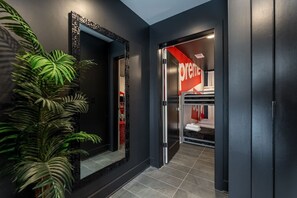 Ein moderner Hotelkorridor mit einem großen Spiegel, einer Topfpflanze und einem roten Schild, das ein Premium-Zimmer kennzeichnet.