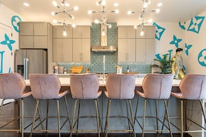 A modern kitchen with six bar stools, a central island, and a decorative wall with blue floral patterns. - Glamour on the Rocks - Nashville's Most Instagrammable Luxury Stay - Sleeps 12 (Nashville)