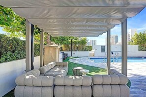 Un'area salotto esterna coperta con una piscina sullo sfondo.