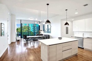 A modern kitchen with a central island, pendant lighting, and a view of a cityscape.