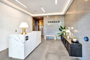 A modern reception area with a marble reception desk, a bench, and a wall-mounted sign that reads 'Sonder'. - 17West 3BR Miami Beach | Pool & Walk to Beach (Miami Beach)
