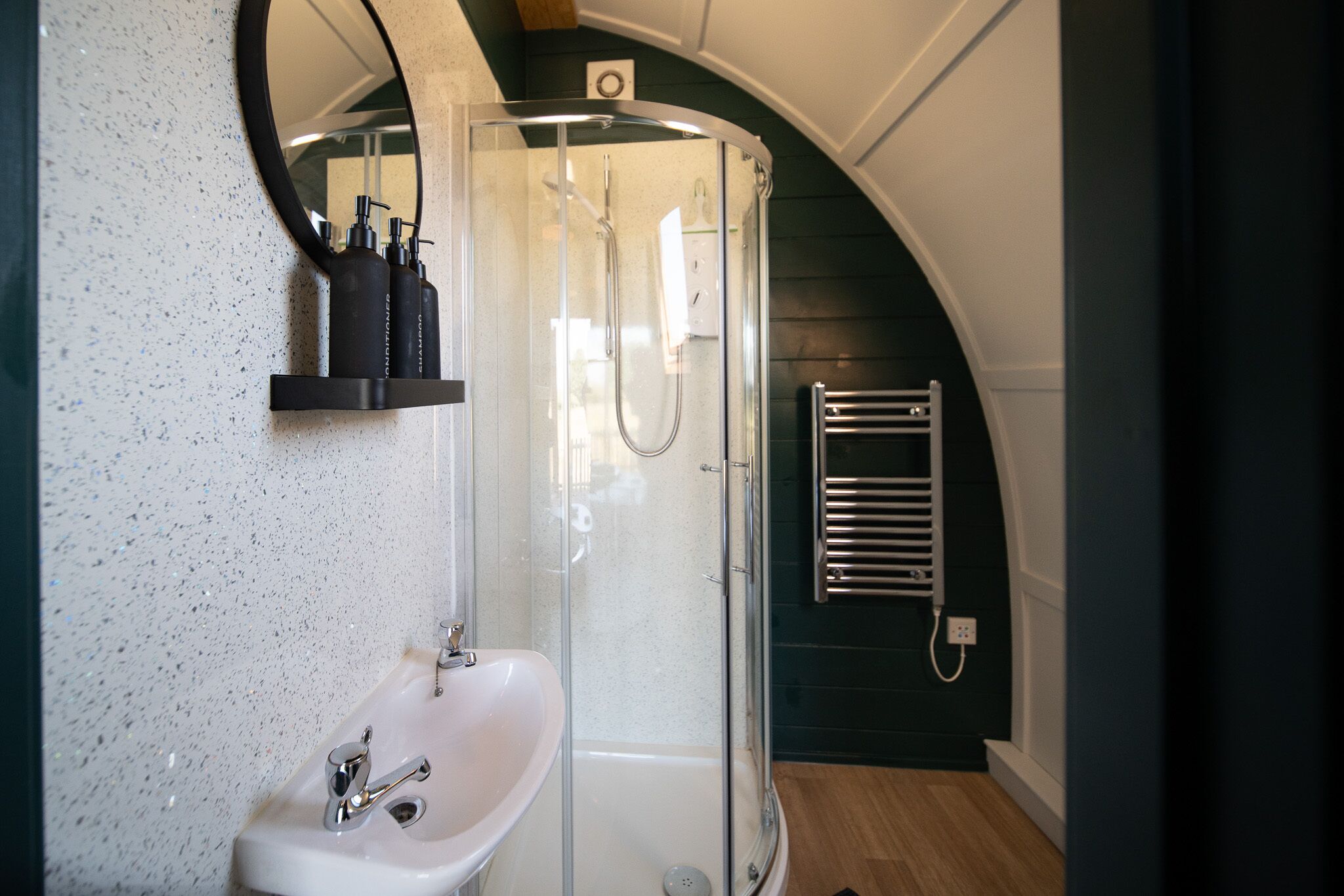 A bathroom with a shower, a sink, and a towel rack.