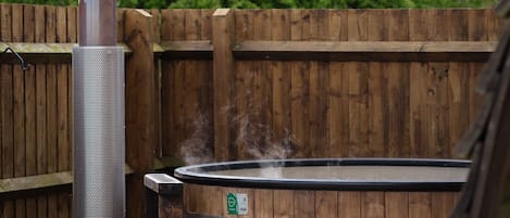 A hot tub with a wooden fence and trees in the background.