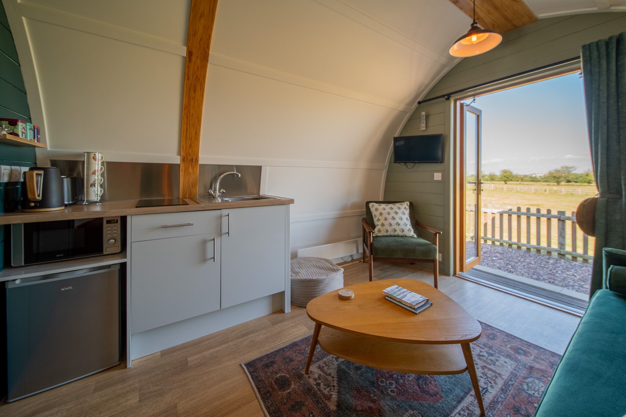 Una cocina compacta con electrodomésticos modernos, un comedor con mesa, y vistas al exterior a través de un ventanal grande.