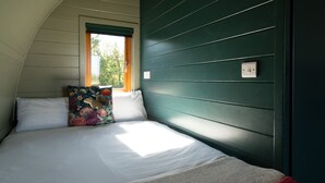 A bedroom with a bed, pillows, a window, and a wall switch.