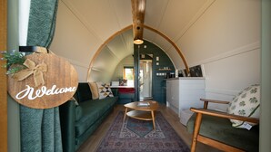 A cozy interior with a curved ceiling, a welcome sign, a sofa, a small table, and a kitchen area.