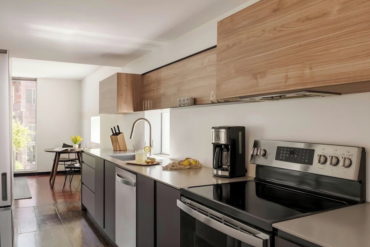 Een moderne keuken met een inbouwoven, koffiezetapparaat en houten kasten.