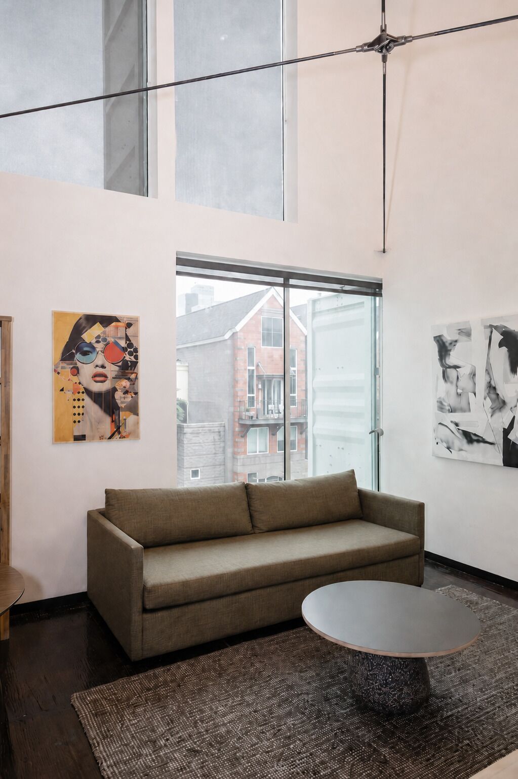 A modern living room with a sofa, a round coffee table, and artwork on the walls.