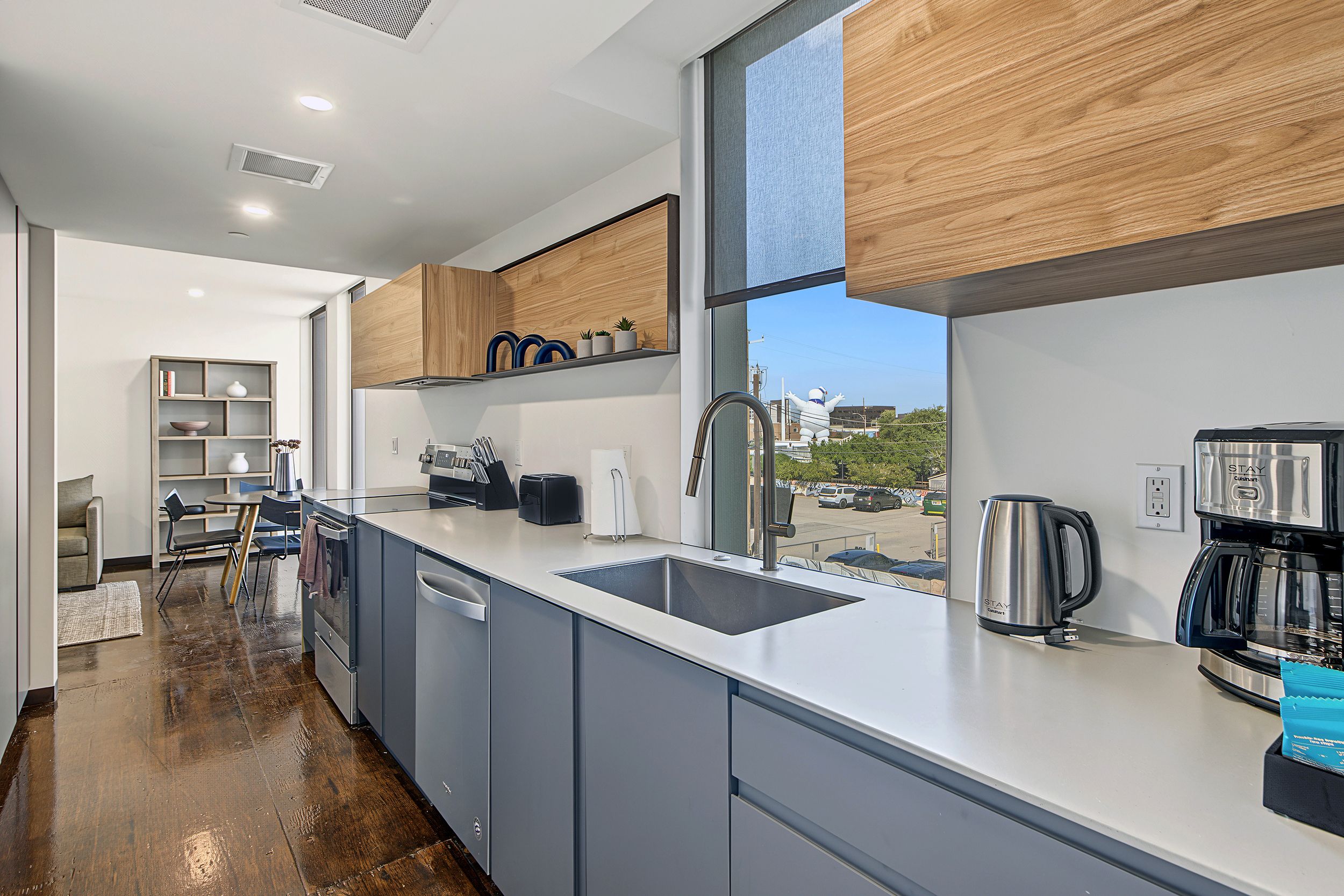 A modern kitchen with a large window, built-in cabinets, and a stainless steel coffee maker.