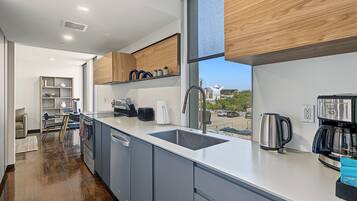 A modern kitchen with a large window, built-in cabinets, and a stainless steel coffee maker.