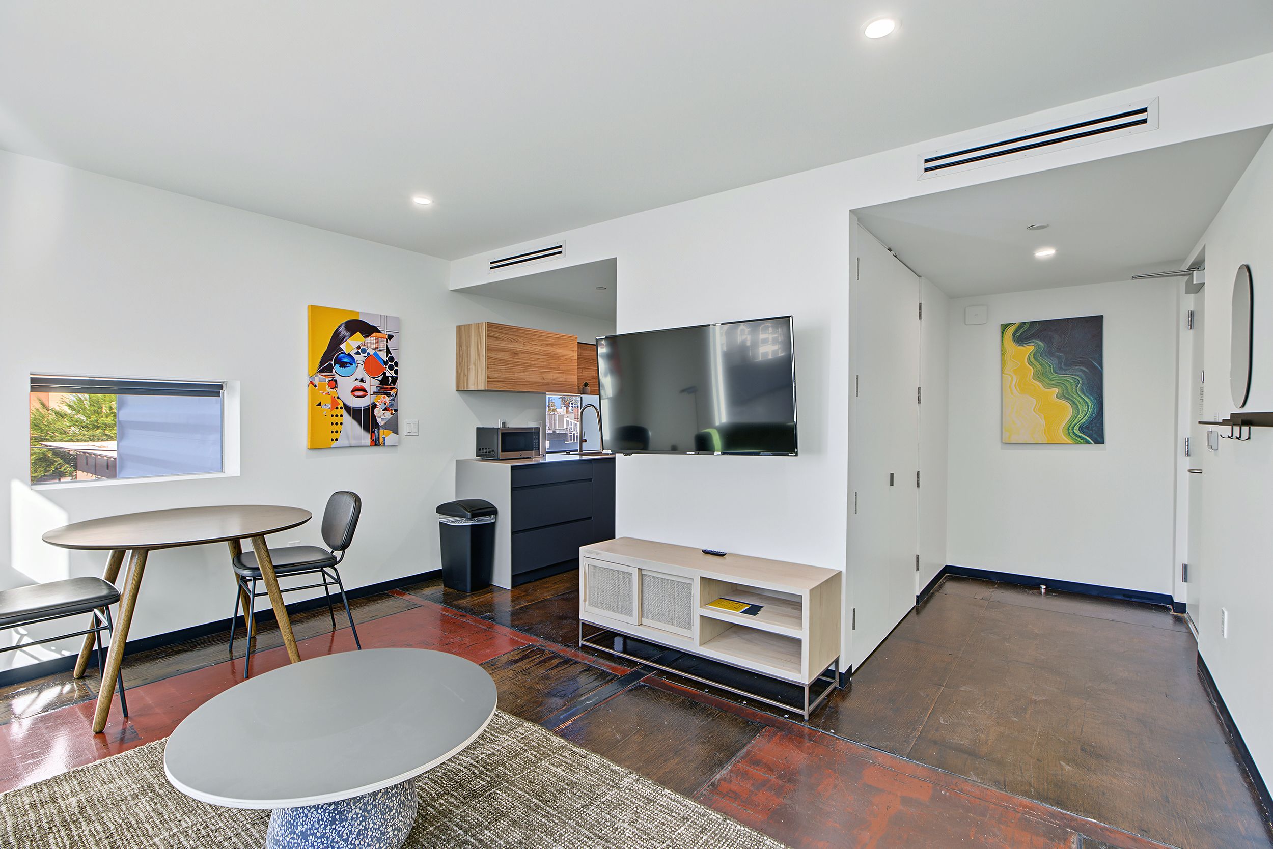 A modern kitchen with a flat-screen TV, a microwave, and wooden cabinets.