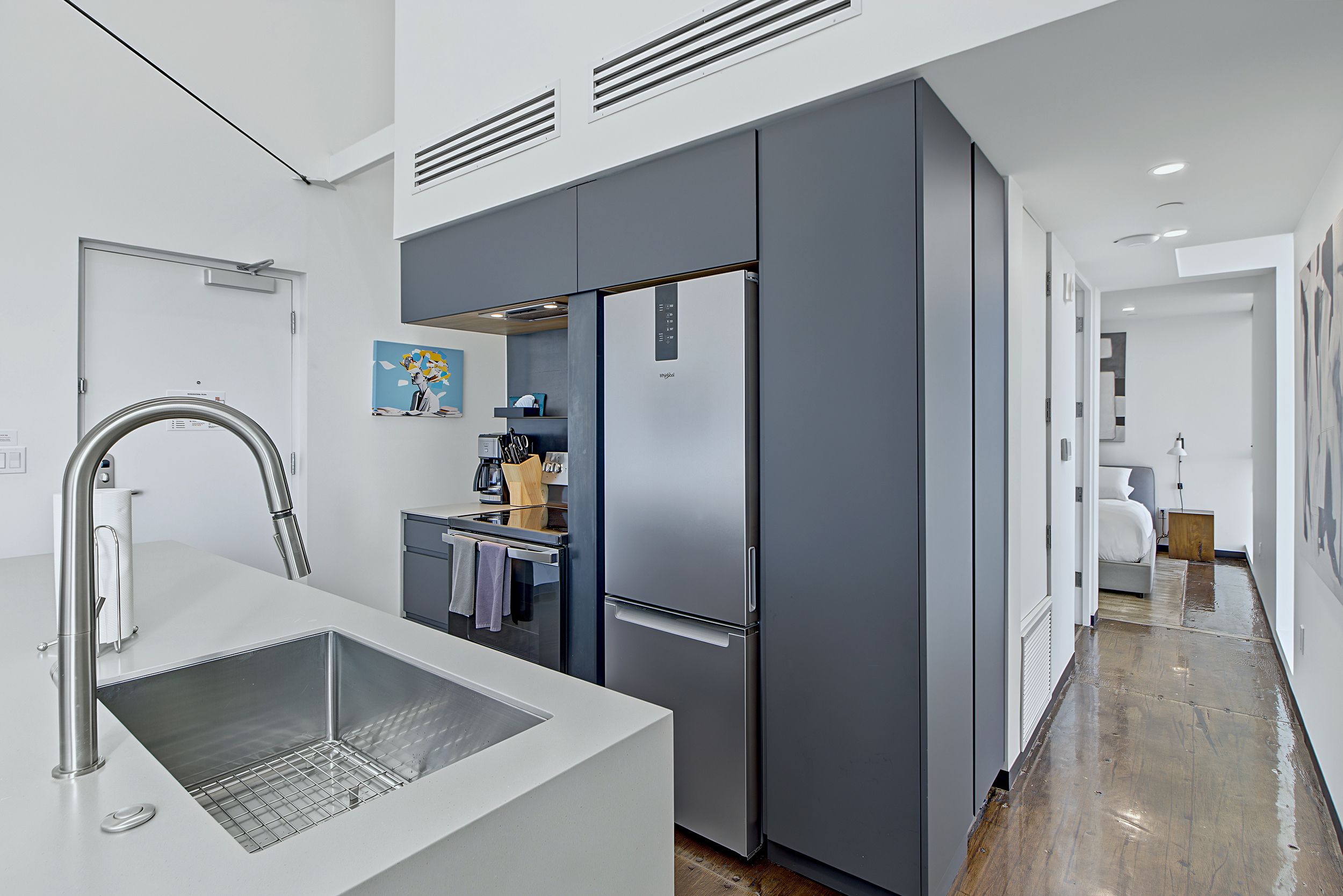 A modern kitchen with a stainless steel sink, a built-in oven, and a large refrigerator.