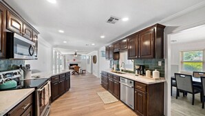 A modern kitchen with dark wood cabinets, stainless steel appliances, and a central island. - Luxury Estate with Pool & Game Room (Kemah Area)