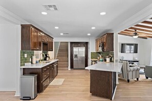 A modern kitchen with wooden cabinets, a stainless steel refrigerator, and a central island.
