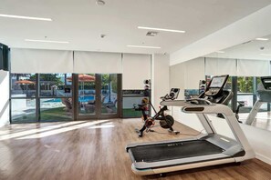 Gym with treadmill and bike facing glass doors onto the pool deck. - 17West 3BR | Balcony, Pool & City Views (Miami Beach)